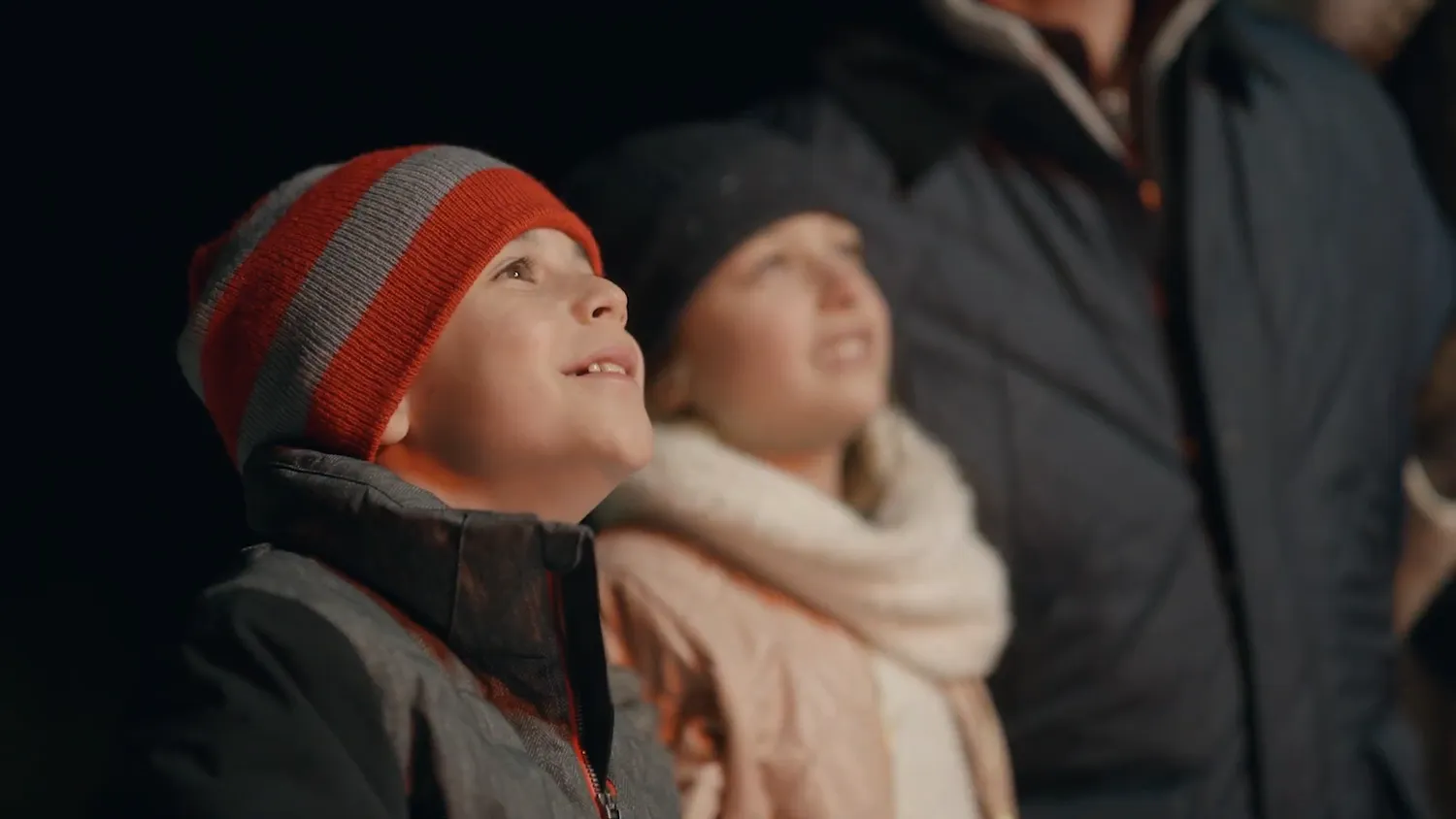 Child in a striped knit hat looks upward at night in the Beaver Creek spot