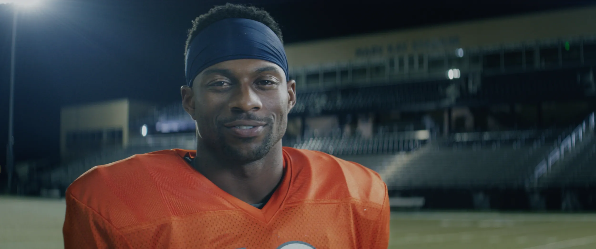 Emmanuel Sanders in an orange football jersey on a field in the OrthoColorado spot