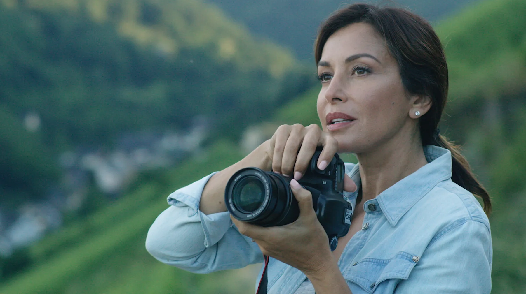 Woman holds a camera against an alpine landscape in See Things Your Way